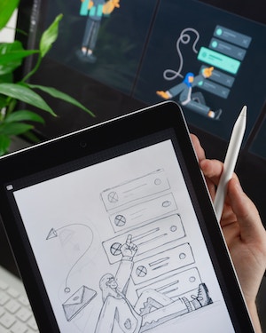 person drawing sketch on tablet with pencil